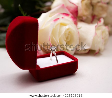 gold ring in red box on the background of roses