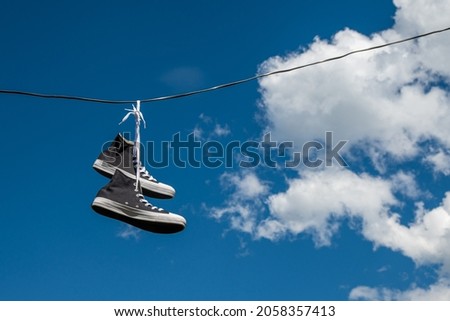 Sneakers hanging on electric wires against a background of blue sky and white clouds. Foto d'archivio © 