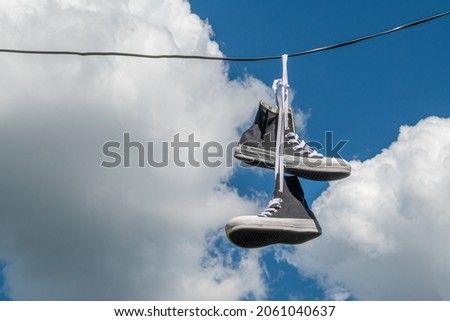 Sneakers hanging on electric wires against a background of blue sky and white clouds. Foto d'archivio © 