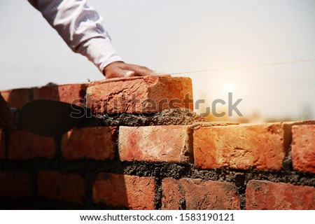 Similar – Foto Bild Arbeiter baut Mauer mit roten Blöcken und Mörtel