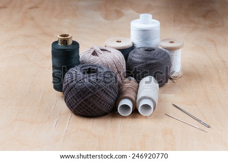 Hanks of yarn. Spools of thread and needles on wooden background.