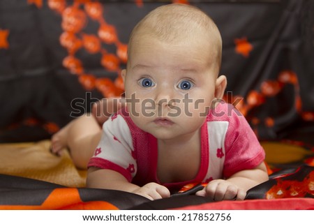 Small cute child surprised, raised his head and crawling on a dark bed