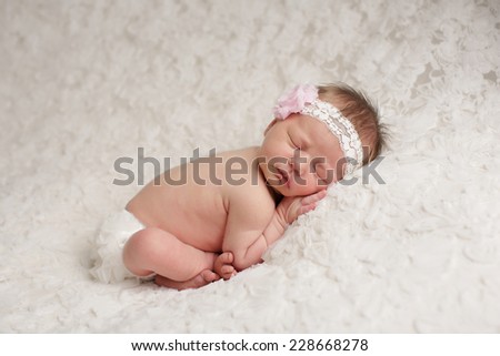 Cute baby girl with feet crossed sleeping on a white lace blanket