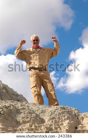 Triumphant senior man after having climbed to the top of a desert mountain.To view all four of the images in this series keyword: khaki/man