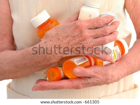 The hands of a senior woman clutching many meds.
