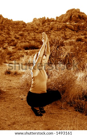 Senior woman practicing yoga at dusk in the desert.