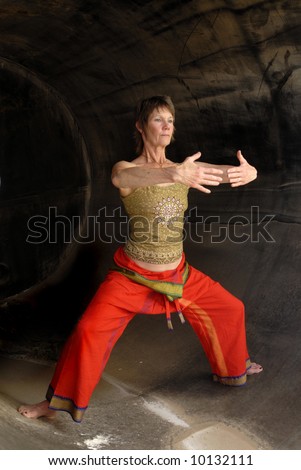 Senior Woman in Asian Yoga Qi Gong influenced pose in a rust cylinder.