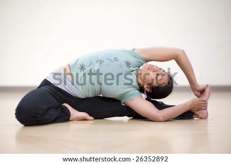 Young asian woman in a seated yoga twist posture.