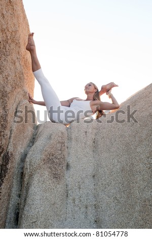 Professional yoga teacher high on a rock in a beautiful natural landscape.