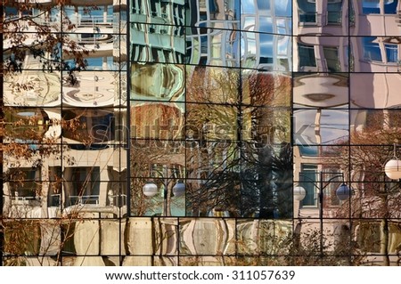 Detail of glass facade of modern office building with reflection of blue sky and clouds.