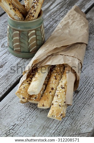 Puff pastry sticks with sesame seeds in a paper bag