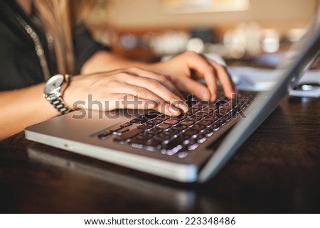 Hands of young business woman in cafe drinking coffee with laptop indoor