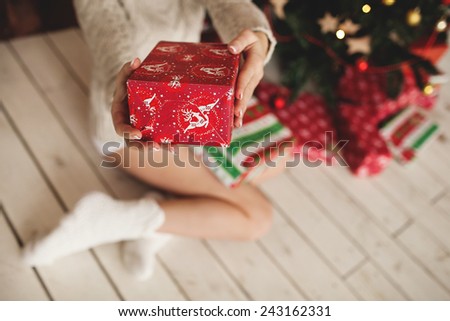 Beautiful woman legs in socks and decorated Christmas tree with gifts