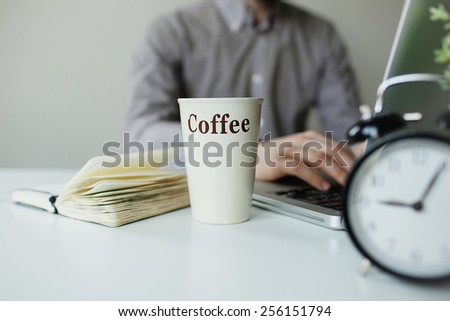 Modern working desk with laptop coffee notepad and alarm clock