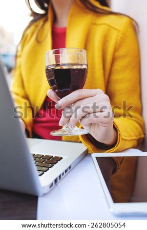 Young woman with glass of red wine tablet and laptop in street cafe