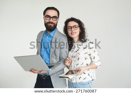 Young hipster man and woman in glasses with laptop and tablet isolated on the blank white background