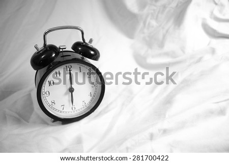 Small Black Alarm Clock on a Bed Sheet; Black and White