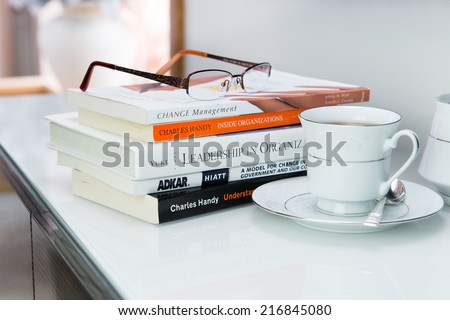 SYDNEY, AUSTRALIA - SEP 5 2014: Illustrative Editorial photo of women\'s reading glasses, books on Leadership / Change Management, tea cup beside. Concept: Empowering Women in Education / Leadership.