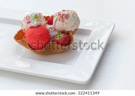 Strawberry ice cream scoops with colorful sprinkles in waffle bowl