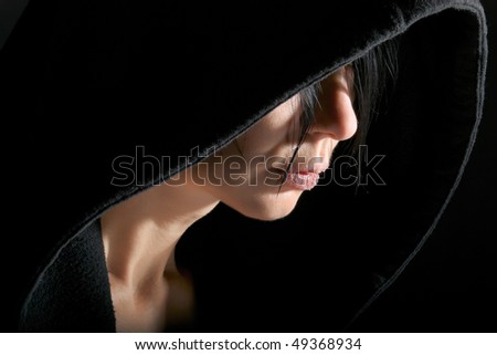 Woman portrait in low key with contour from hood