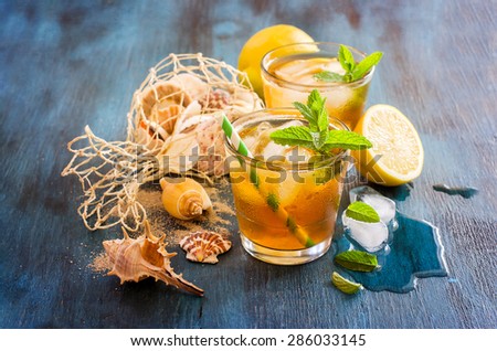 Fresh cold iced tea with mint, ice cubes and lemons, refreshing summer drink, sea shells