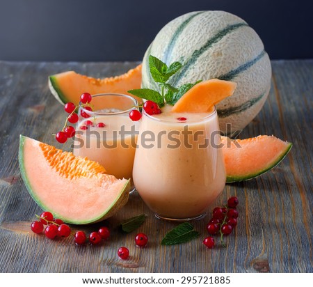 Healthy smoothie vitamins drink with red currant fresh berries, mint and cantaloupe melon, shake with yogurt for breakfast on wooden rustic background, summer harvest beverage, diet concept