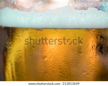 Beer with beer foam in glass, selective focus on edge of foam and liquid level