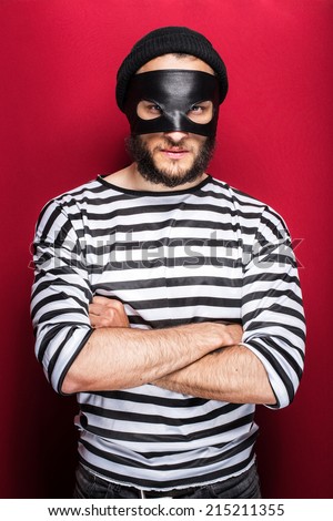Angry thief with mask on red background