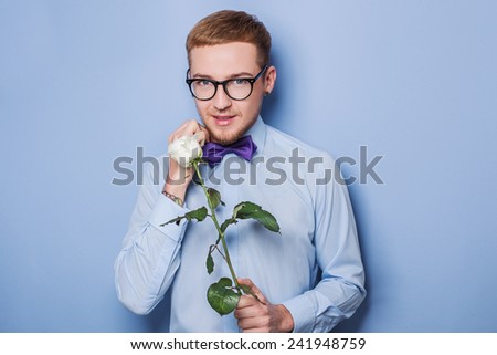 Cute young men with flower. Date, birthday, Valentine. Studio portrait over blue background