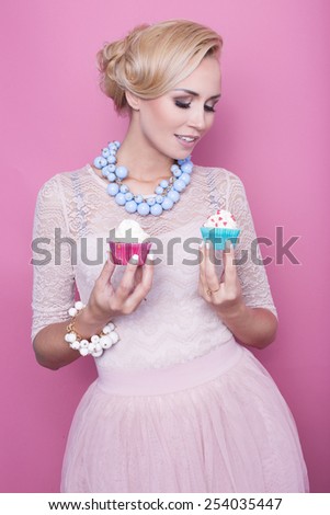 Beautiful middle aged women hold colorful sweets. Soft colors. Studio portrait over pink background
