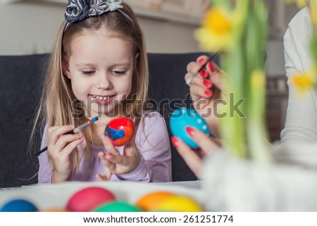Easter, family, holiday and child concept - close up of little girl and mother coloring eggs for Easter. Cozy home atmosphere. Easter