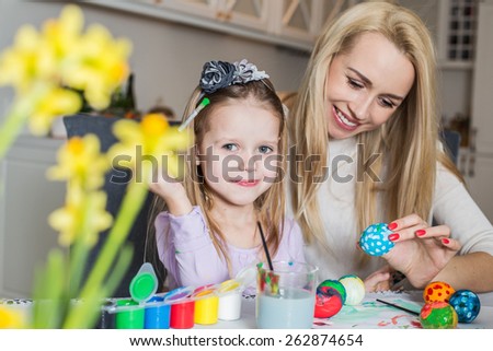 Young mother and her beautiful daughter painting Easter eggs. Easter, family, holiday and child concept