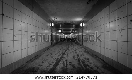 An urban pedestrian underpass with graffiti and low lighting making it an intimidating location.