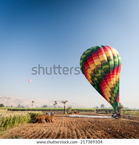 A view over the Nile floodplain near Luxor, Egypt, of a group of tour operators inflating a hot air balloon.