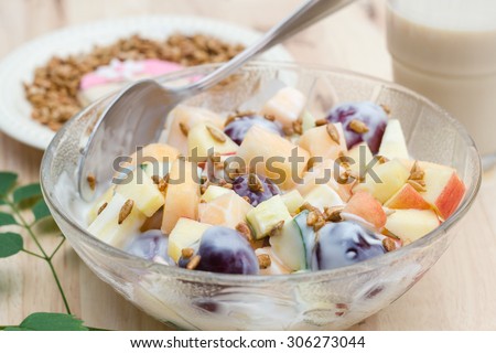 Fruits salad with plain low fat yogurt eat with cookie mom cartoon face with sunflower seeds honey roasted  and a glass of soil milk.