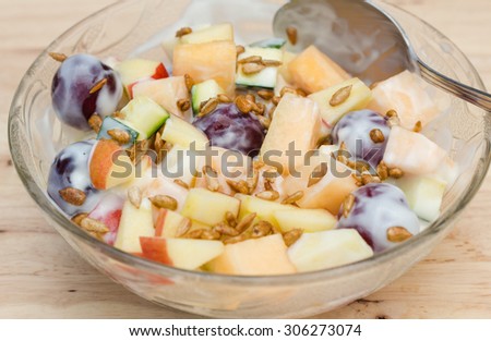 Fruits salad with plain low fat yogurt topping with sunflower seeds honey roasted.