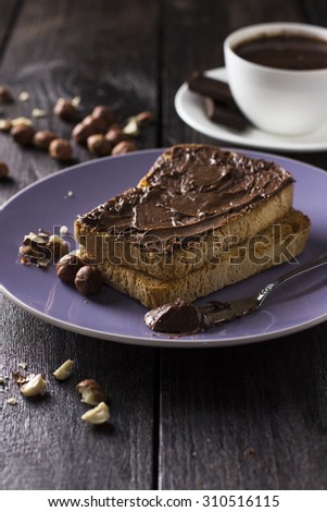 Toast with chocolate paste and nuts on a wooden background