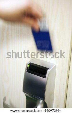 A blurry hand with a keycard, opening the electronic lock on a hotel door, high iso