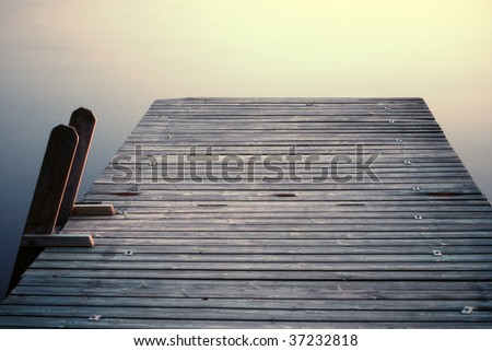 Bathing platform with wood ladder in calm water an summer evening