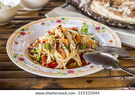 Papaya salad Thailand food or Som Tum Thai with Grilled Fish on wooden table. Traditional Thai food. Thai papaya salad