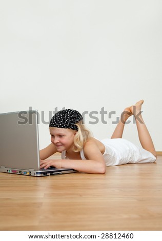 Little blonde sitting on the floor with modern computer