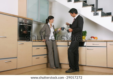 Business-couple standing in kitchen with cups