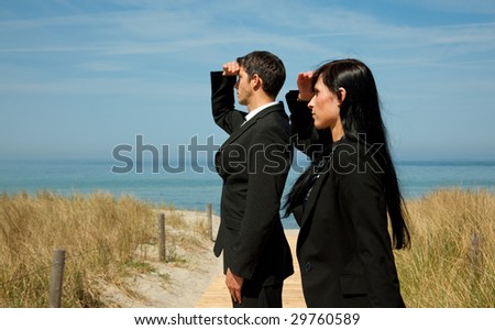 Formal man and woman as investmentteam standing on the sunny beach