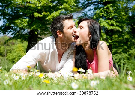 Funny couple lying in park green grass
