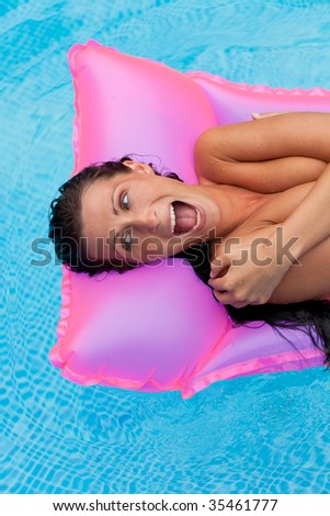 Air bed floating happy woman smiling laughing in a swimming-pool relaxing and enjoying vacations summertime