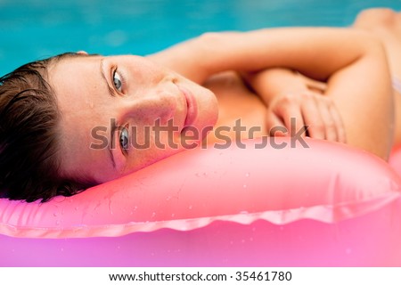 Air bed floating happy woman smiling  in a swimming-pool relaxing and enjoying vacations summertime