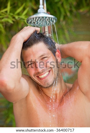 Hair washing man under garden shower showering hair and body smiling beauty