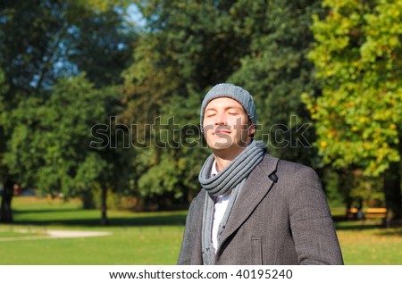 Man walking park enjoying sunbeams with closed eyes