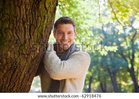 Portrait of relaxing man on tree enjoying golden autumn fall season