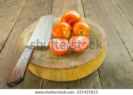 Tomatoes with a knife in the corner of a butcher block.